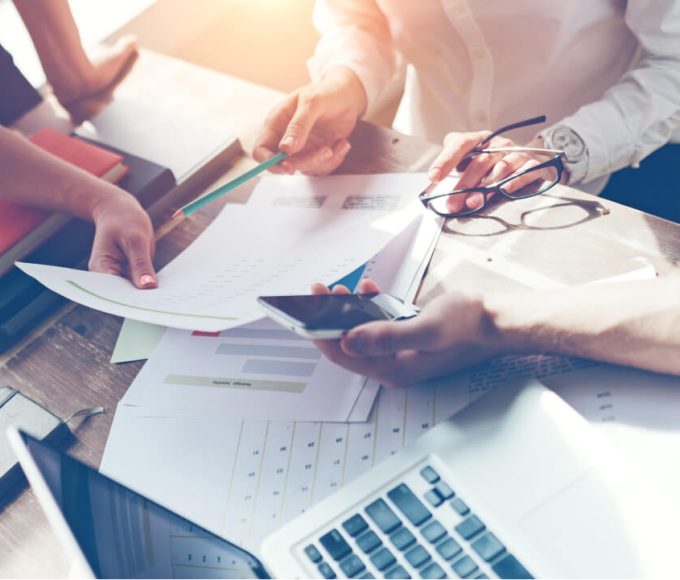 view of documents on a table with various individuals discussing the information